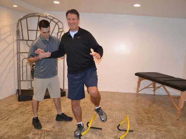 Physical therapist assisting a man with balance exercises during post-op and injury recovery session.